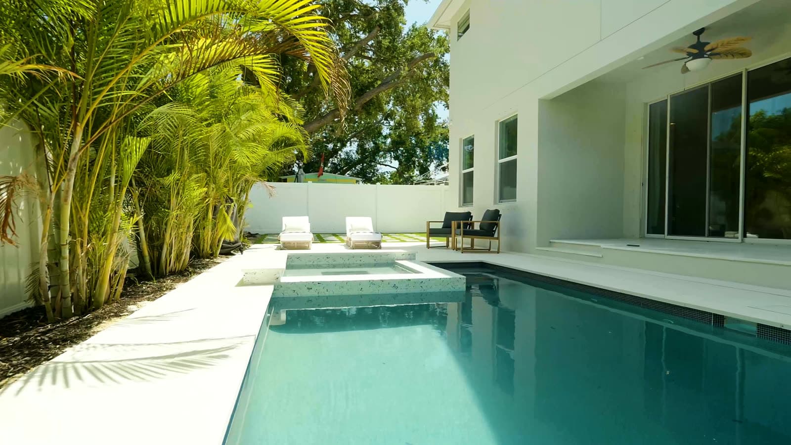 A LIV Pools custom pool with a raised spa and lush landscaping behind a modern Tampa Bay home